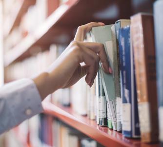 Hand pulling book from shelf