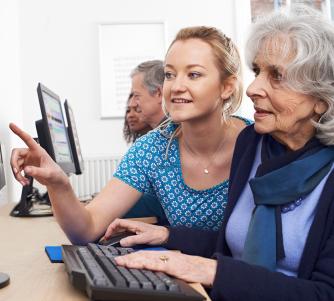Lady helping senior with computer