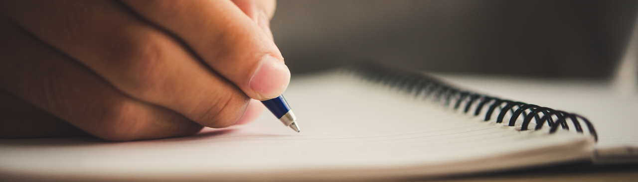 A closeup of a person's hand writing with a pen