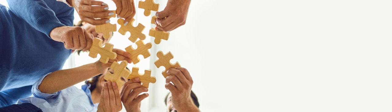 socialworker_hero.jpg people holding wooden puzzle pieces in a circle
