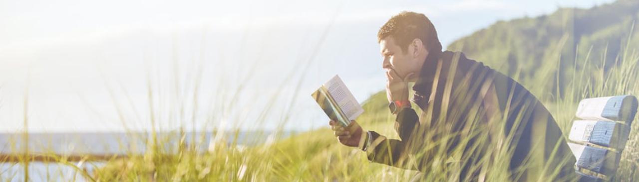 manreading.jpg Man reading on a bench by some water